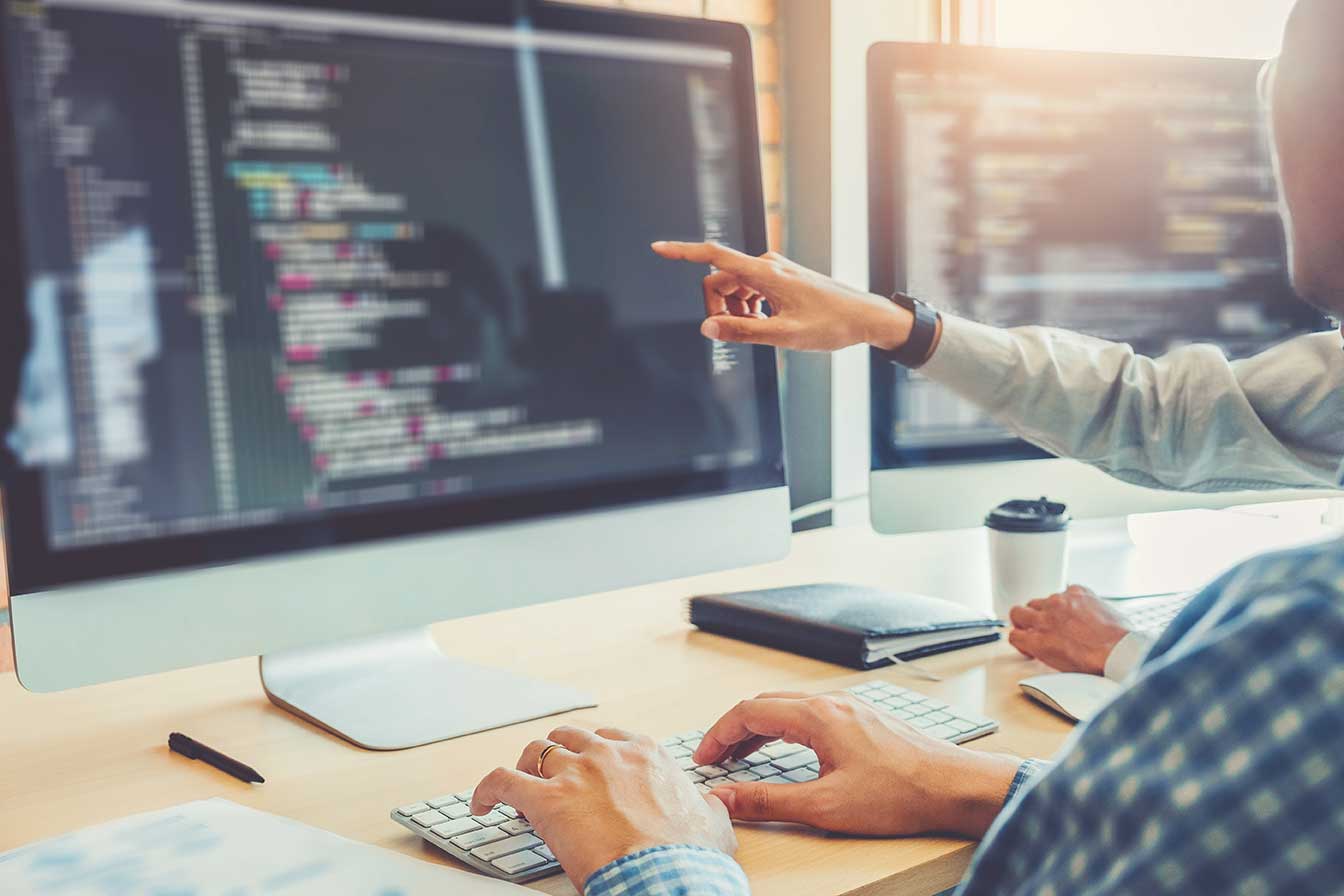 Person pointing at computer screen with code